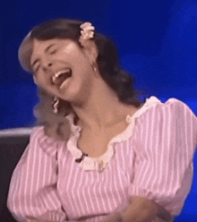 a woman in a pink and white striped shirt is laughing .