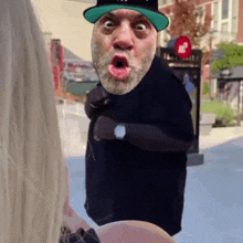a man with a beard is wearing a green hat and a black shirt