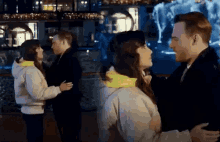 a man and a woman are standing next to each other in front of a fountain .
