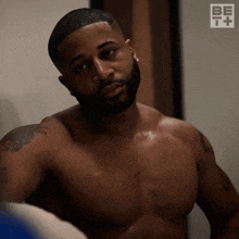 a shirtless man is looking at himself in a mirror with a be t logo in the background