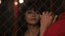 a woman is behind a chain link fence looking at a man