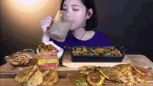 a woman drinks from a glass while eating food on a table