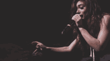a woman singing into a microphone with her hand on her face