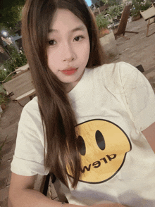 a girl wearing a white t-shirt with a yellow smiley face and the word alem on it