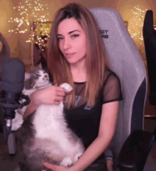 a woman is holding a cat in front of a microphone that says net ab on it