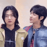 two young men are standing next to each other in a room and looking at each other .