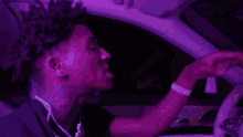 a person holding a steering wheel in a car with purple lights behind them