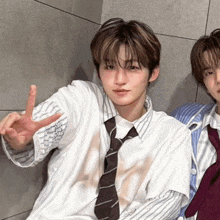 a man wearing a tie and a striped shirt giving a peace sign