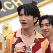 a group of young men are standing next to each other . one of the men is wearing a name tag that says keen .