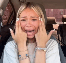 a woman is crying while sitting in a car with her hands on her face