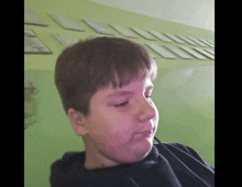 a young boy is making a funny face in front of a green wall with pictures on it