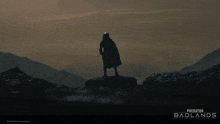 a poster for predator badlands shows a silhouette of a person holding a sword