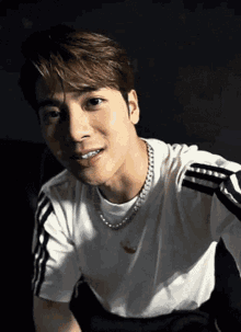 a close up of a man wearing a white t-shirt and a necklace