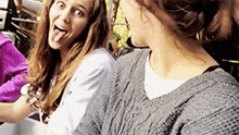 a woman sticking her tongue out while sitting next to another woman .