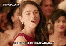 a woman in a red dress is standing in front of a crowd and making a funny face .