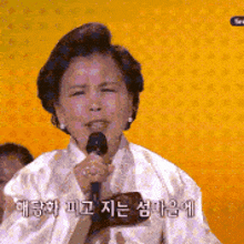 a woman singing into a microphone with chinese writing on the bottom