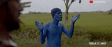 a man with blue paint on his body is standing in a field with a youtube logo above him