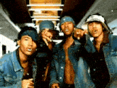 a group of men wearing denim jackets and bandanas pointing at the camera