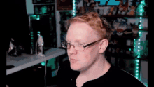 a man with red hair and glasses is sitting in front of a computer