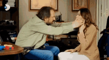 a man is putting his hand on a woman 's face with the letter h on the bottom right