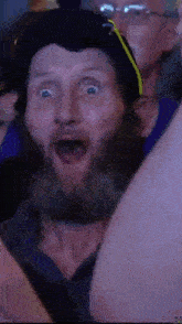 a man with a beard is making a funny face while watching a game .
