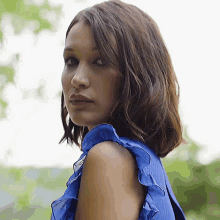 a woman is wearing a blue top with ruffles on the sleeves