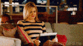 a woman is sitting on a couch with a tablet