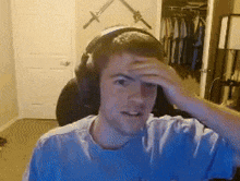 a young man wearing headphones holds his hand to his head