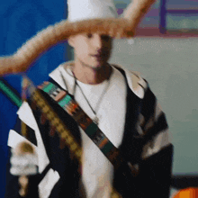 a blurry picture of a man wearing a white hat and a black jacket with a necklace that says ' iam '