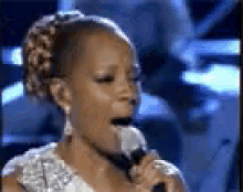 a woman is singing into a microphone while wearing earrings .