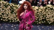 a woman with red hair is walking down a runway in a pink suit .