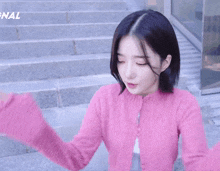 a woman in a pink sweater covering her face