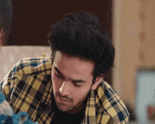 a man wearing a plaid shirt is looking down