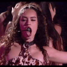 a woman is singing into a microphone while wearing a choker .