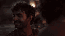 a man with a beard is talking to another man in the dark