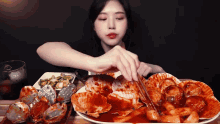 a woman is eating a plate of seafood with chopsticks