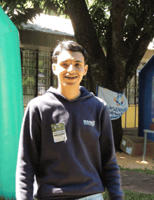 a man wearing a parana sweatshirt smiles in front of a tree