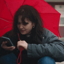 a woman is sitting under a red umbrella with her hand on her head