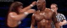 a man without a shirt is being attacked by a woman while a referee watches .