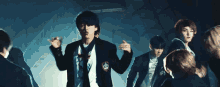 a group of young men in suits and ties are dancing in a dark room .