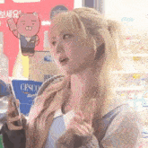 a girl with blonde hair is holding a cell phone in front of a cesco sign
