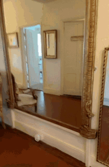 a large mirror is in a hallway with a chair