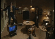 a man is sitting on a couch in a living room with a clock on the wall above him