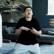 a man in a black shirt and white shorts is dancing in a living room