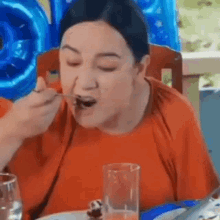 a woman is sitting at a table eating food with a fork and spoon .