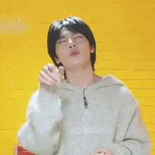 a young man wearing a white sweater is making a funny face .