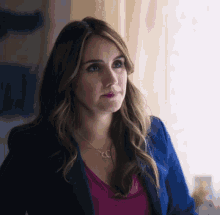 a woman wearing a blue jacket and a necklace with the letters cc on it