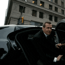 a man in a suit getting out of a car