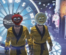 two men in robes with smiley faces on their heads are standing in front of a spinning wheel .