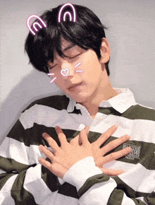 a man wearing a green and white striped shirt has his hands on his chest and a heart on his face